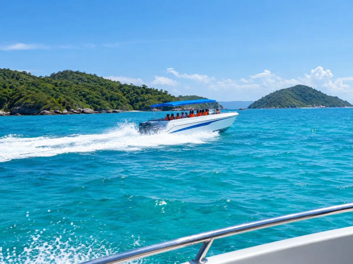 Ein weißes Schnellboot mit blauem Verdeck fährt über türkisfarbenes Wasser auf grüne Inseln zu